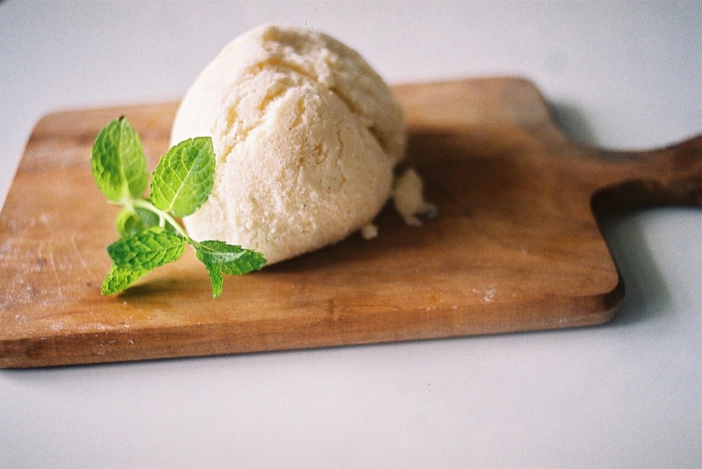 A scoop of vanilla bean ice cream on a wooden board